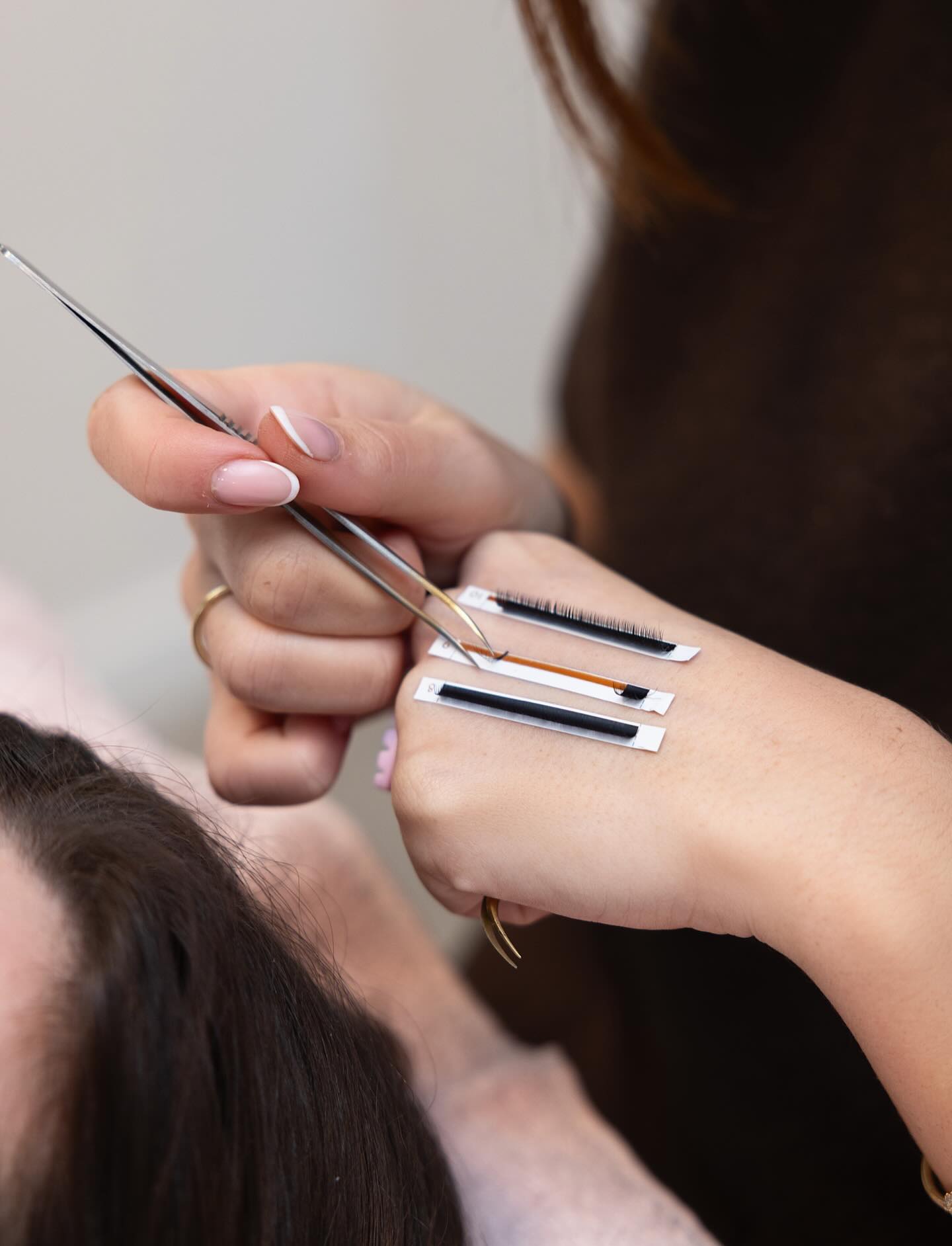 Een hand met handgemaakte wimperwaaiers en een pincet